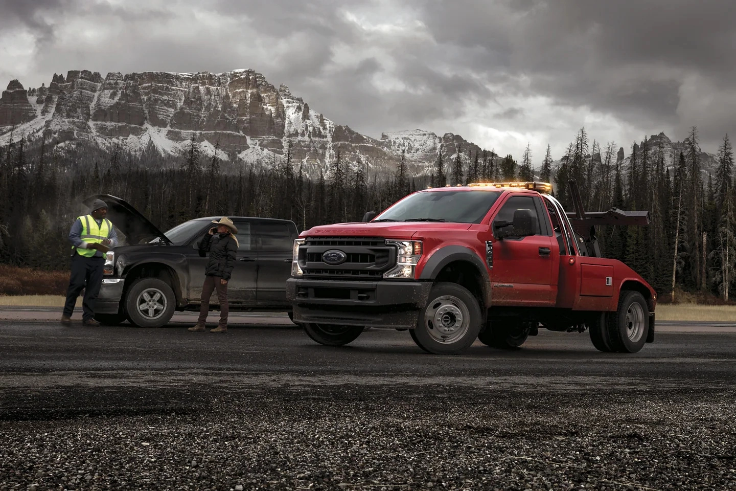 2 men standing near 2 ford super duty trucks with mountains at the background