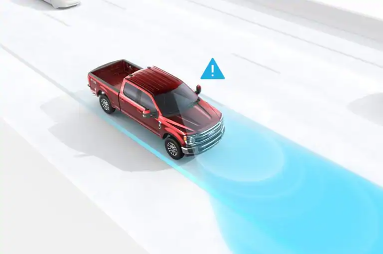 A digital rendering of a red Ford F-450 XLT pickup viewed from above, showing a blue radar-style detection zone trailing the truck with a warning triangle icon, illustrating one of the truck's driver-assist safety features.