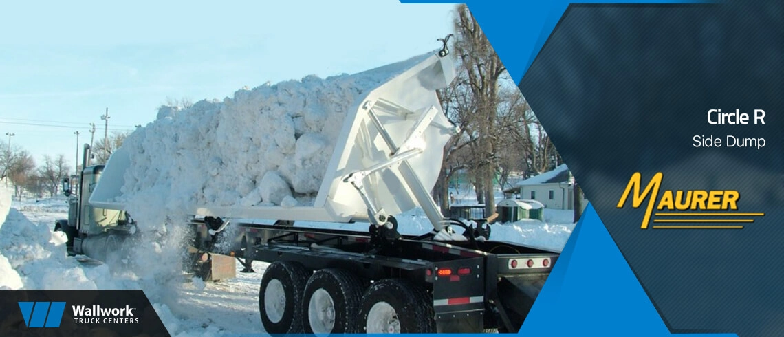 Circle R side dump trailer tilted mid-dump unloading a large pile of snow onto a snow-covered lot, pulled by a semi-truck on a bright winter day